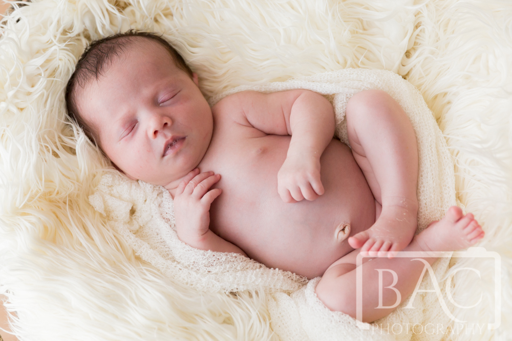 Newborn baby girl sleeping pose on white rug
