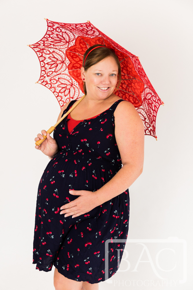 studio maternity portrait with red umbrella