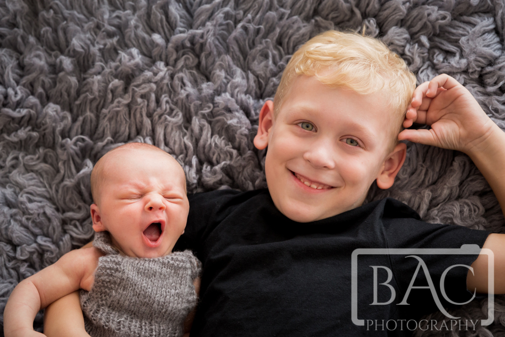 portrait of big brother with newborn baby looking right at camera