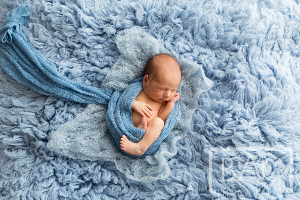 Newborn boy portrait on big blue rug