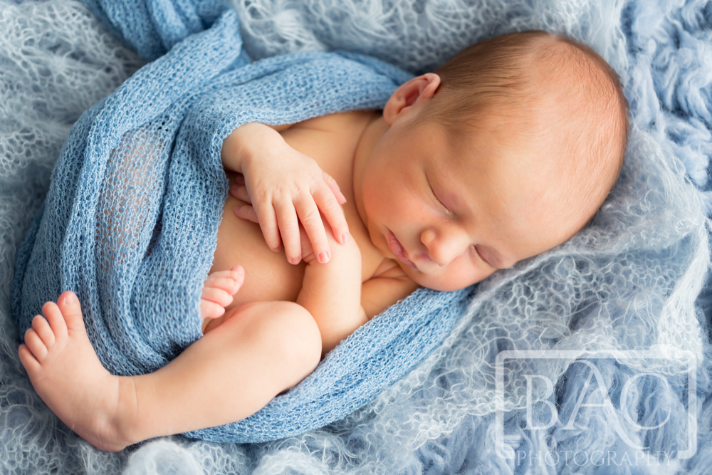 Newborn baby boy on blue rug