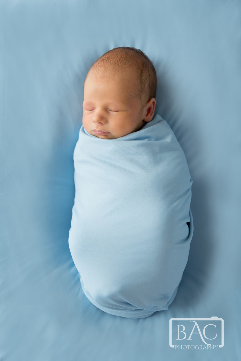 Newborn baby boy in blue all wrapped up