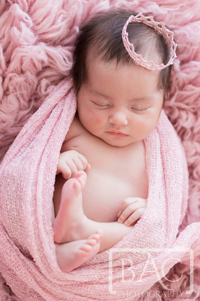 Newborn girl portrait wrapped in pink