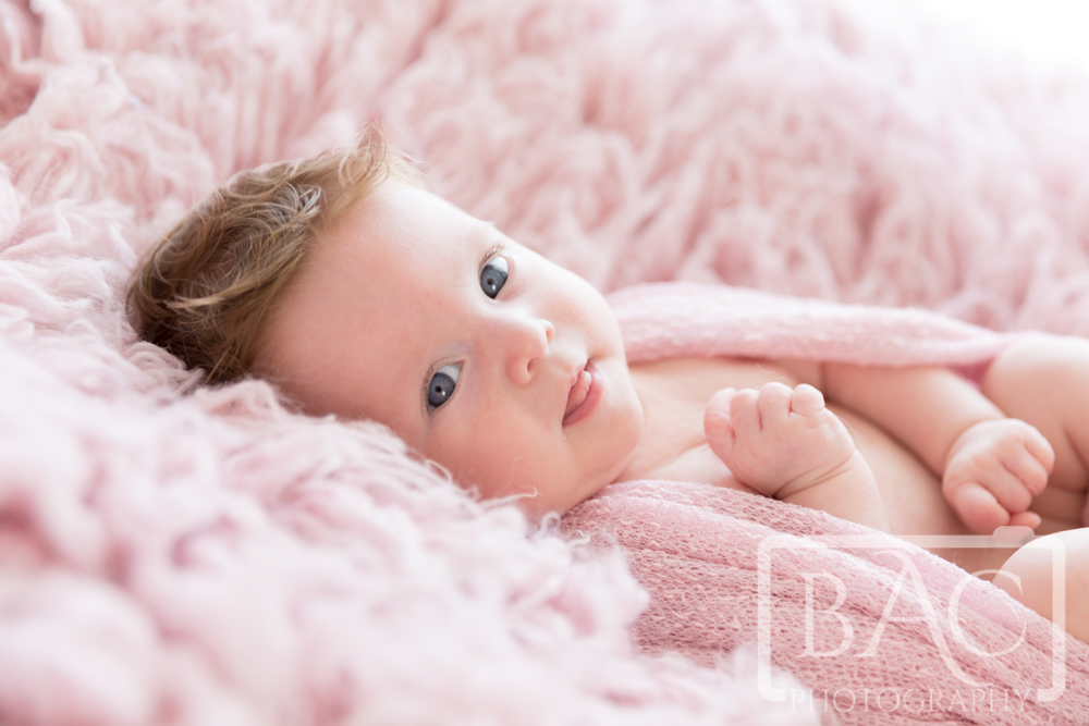 Newborn baby girl portrait on pink rug