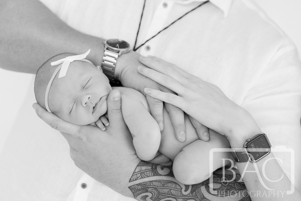 Newborn with parents hands studio portrait