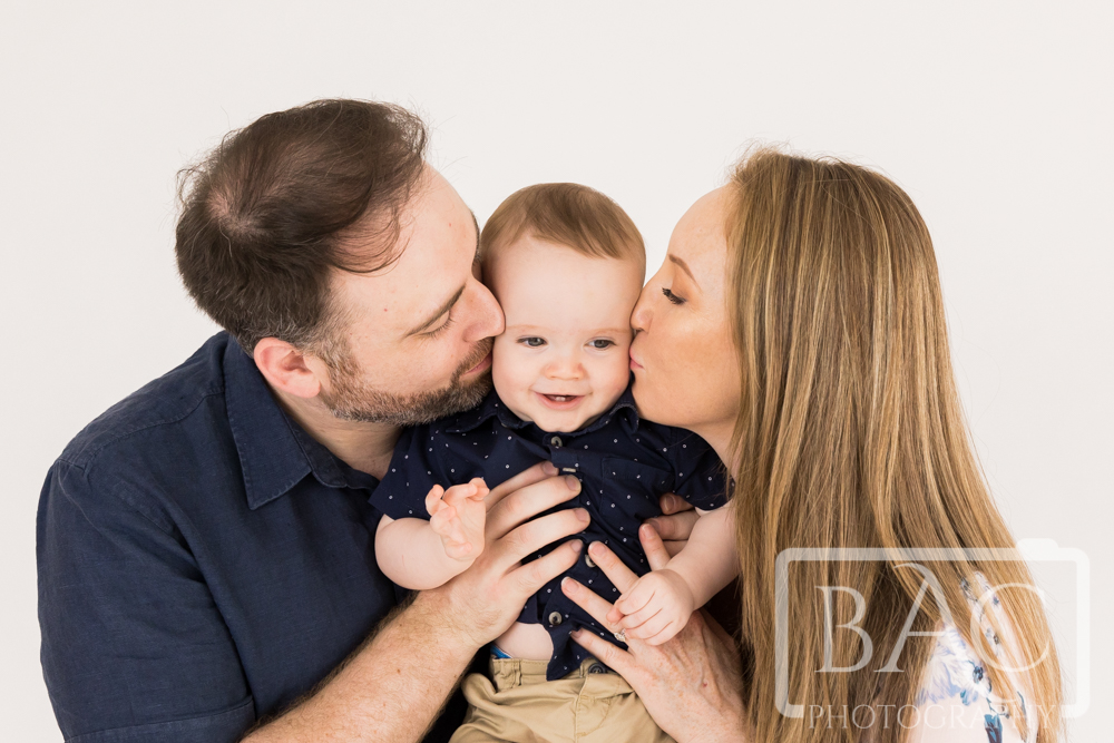 parents kissing toddler portrait
