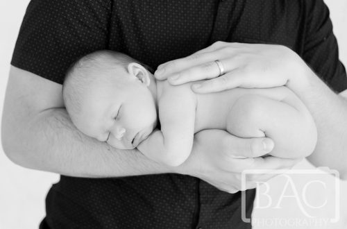 sleeping newborn in dads arms portrait