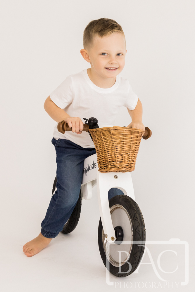 3 year old riding bike studio portrait