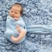 chubby swaddled newborn on blue rug