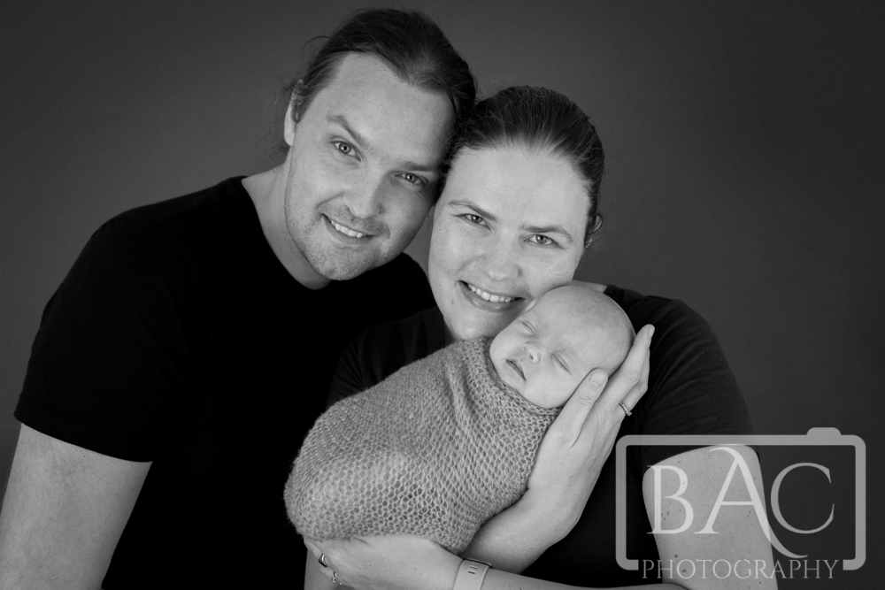 family of 3 mum dad and newborn studio portrait black and white