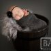 swaddled newborn studio portrait in black tub tiny hands