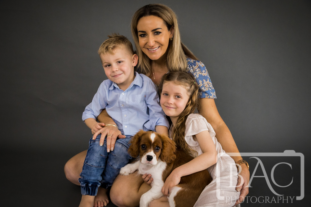 mum and kids with new puppy studio portrait