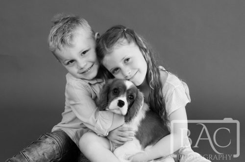 young kids cuddling new puppy studio portrait