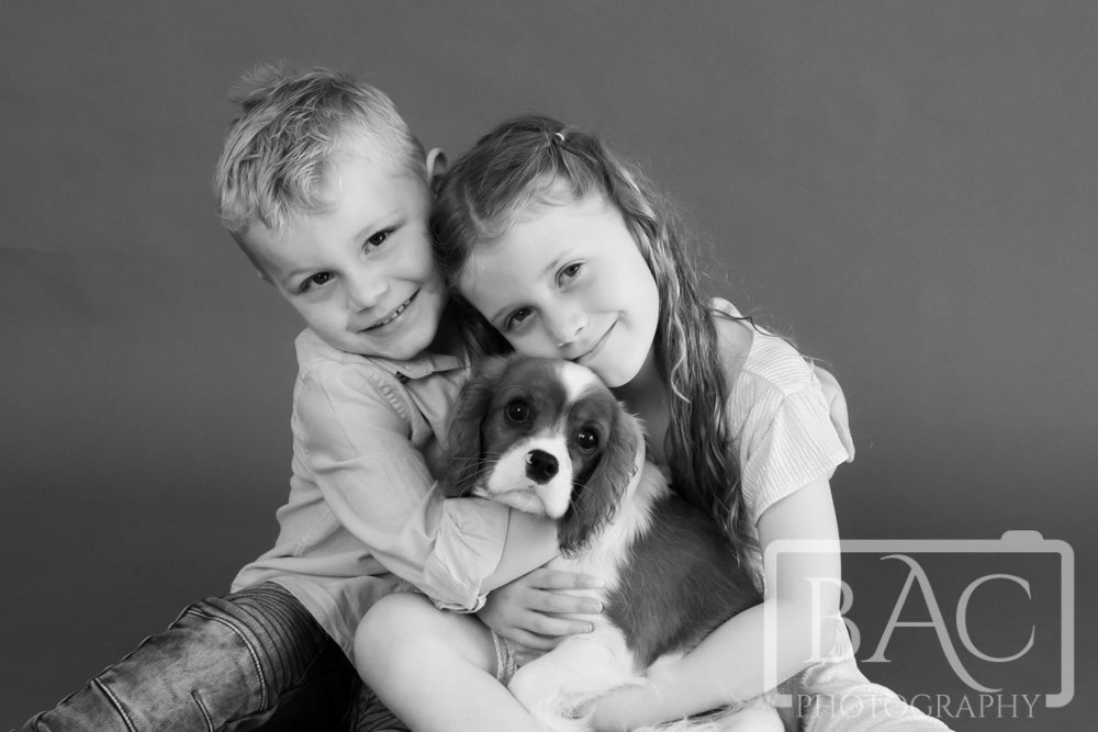 young kids cuddling new puppy studio portrait