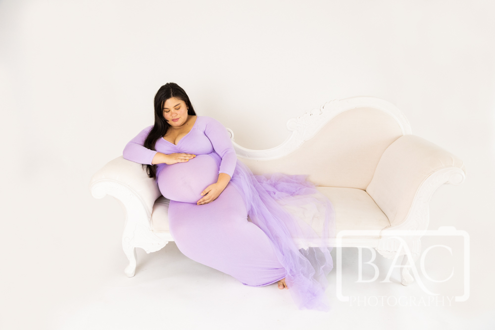 studio maternity session on couch purple gown