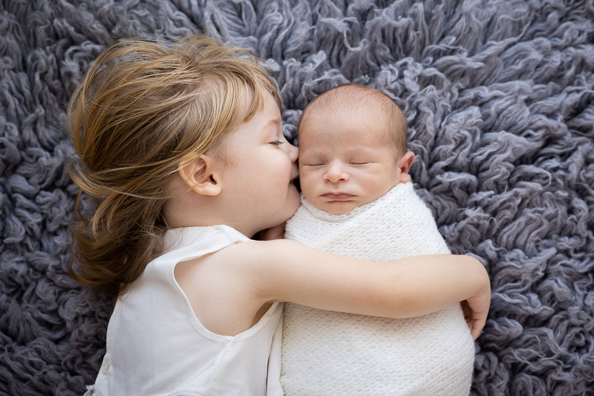 Sibling newborn hug